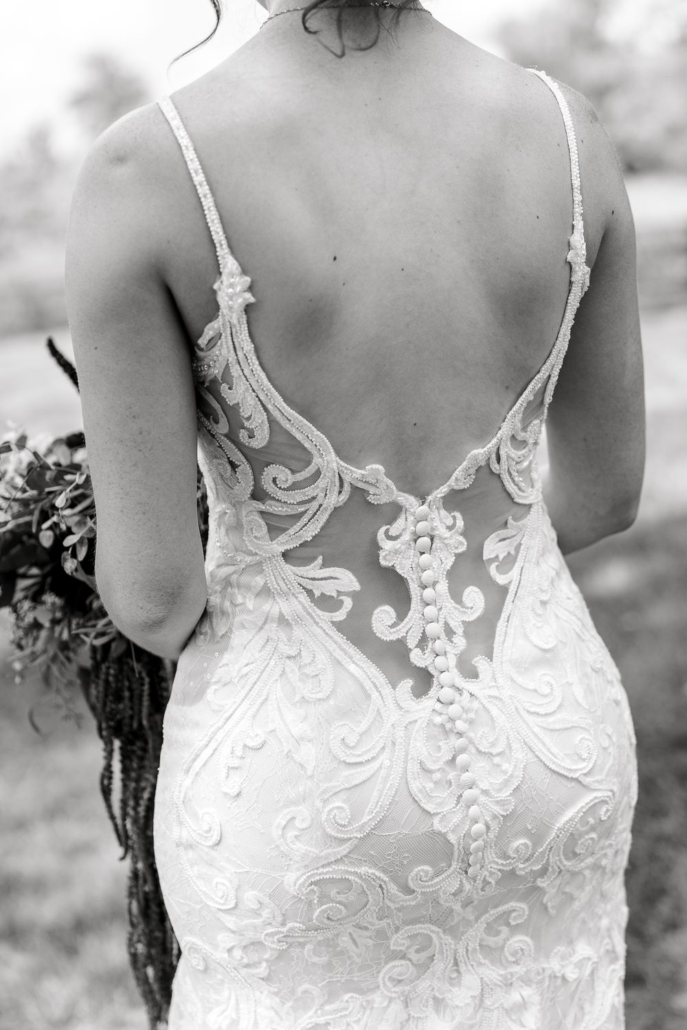 Close-up of intricate lace detail on back of wedding gown in black and white.