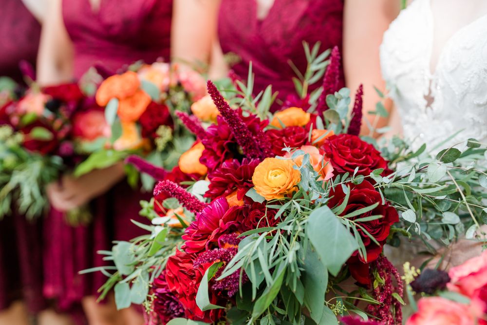 Vibrant wedding bouquet with deep red flowers and lush greenery.