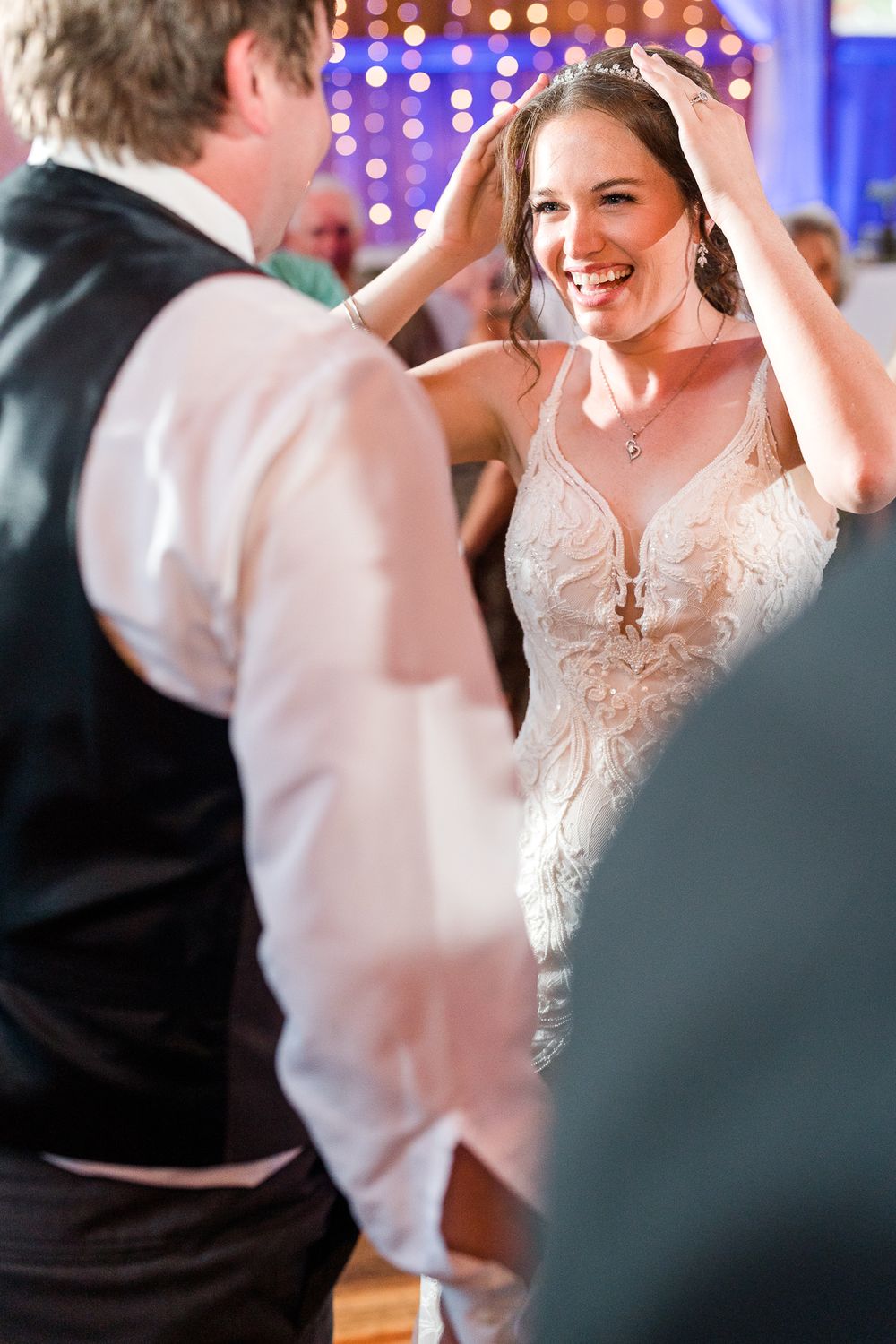 A bride dances with joy under purple lighting at her wedding reception.