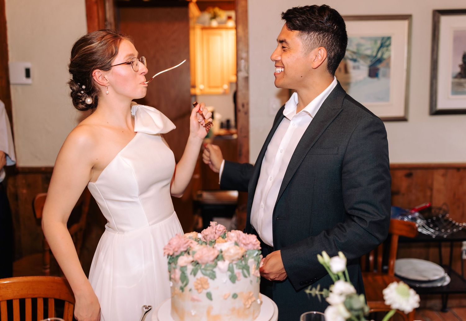 Couple enjoying a playful moment with their wedding cake at the reception.