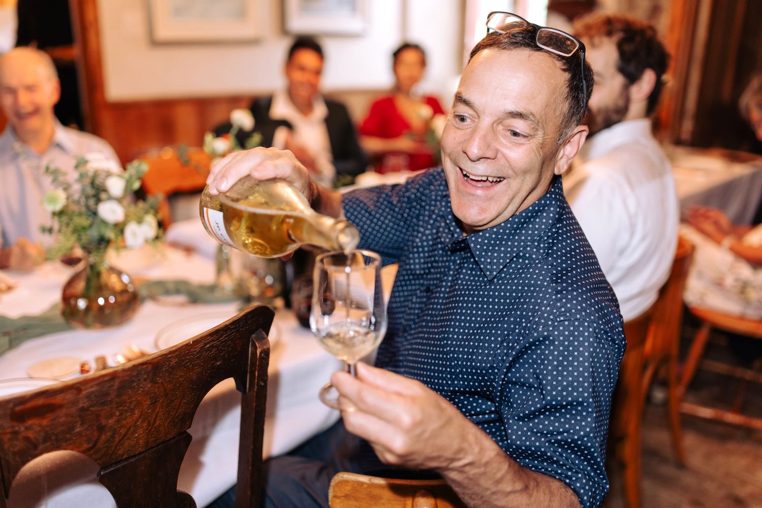 Wine being poured into a glass at an elegant dinner gathering.