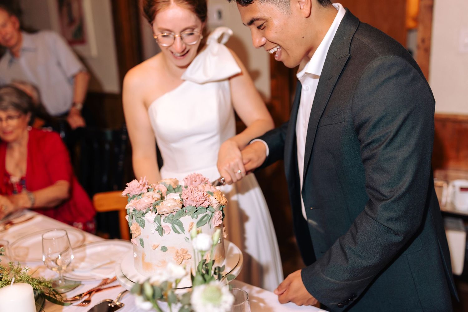 Wedding couple sharing a moment while cutting their floral-decorated wedding cake.