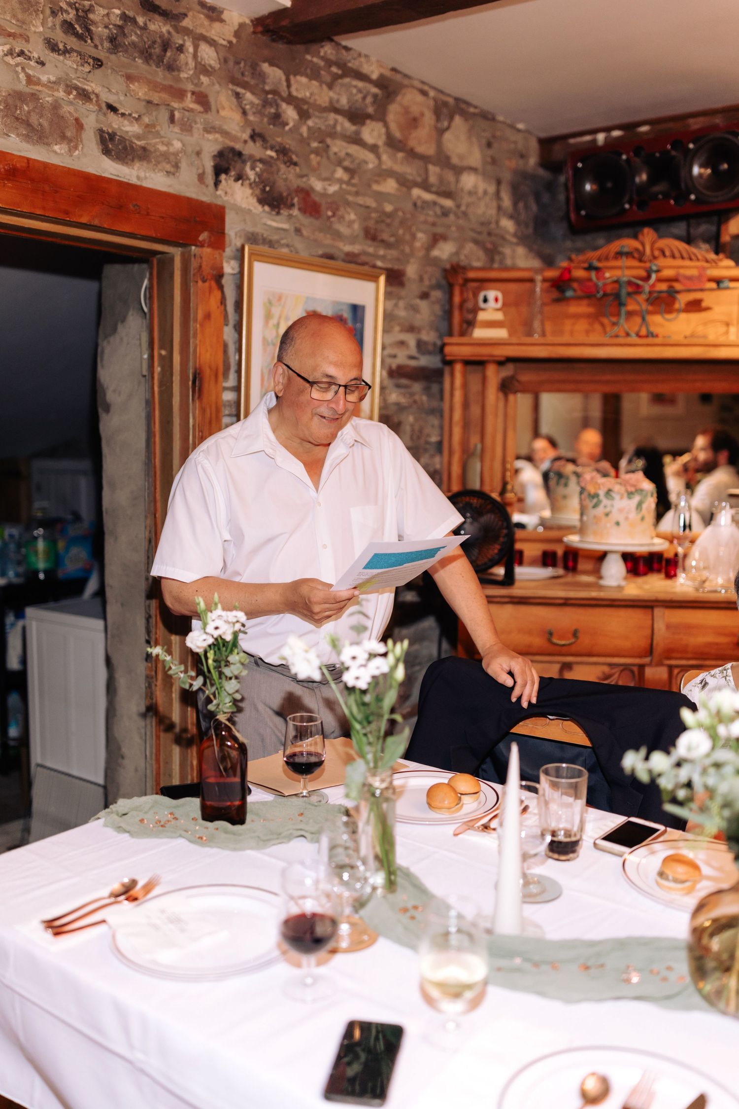 Elegant dinner setup in a rustic stone-walled restaurant with wine glasses and floral centerpieces.