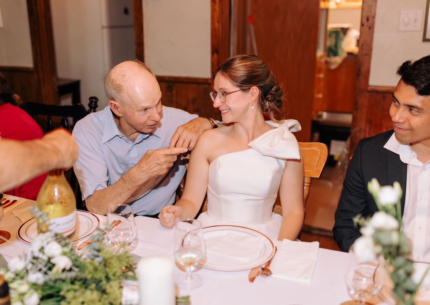 Intimate wedding reception dinner with white tablecloths and floral decorations.