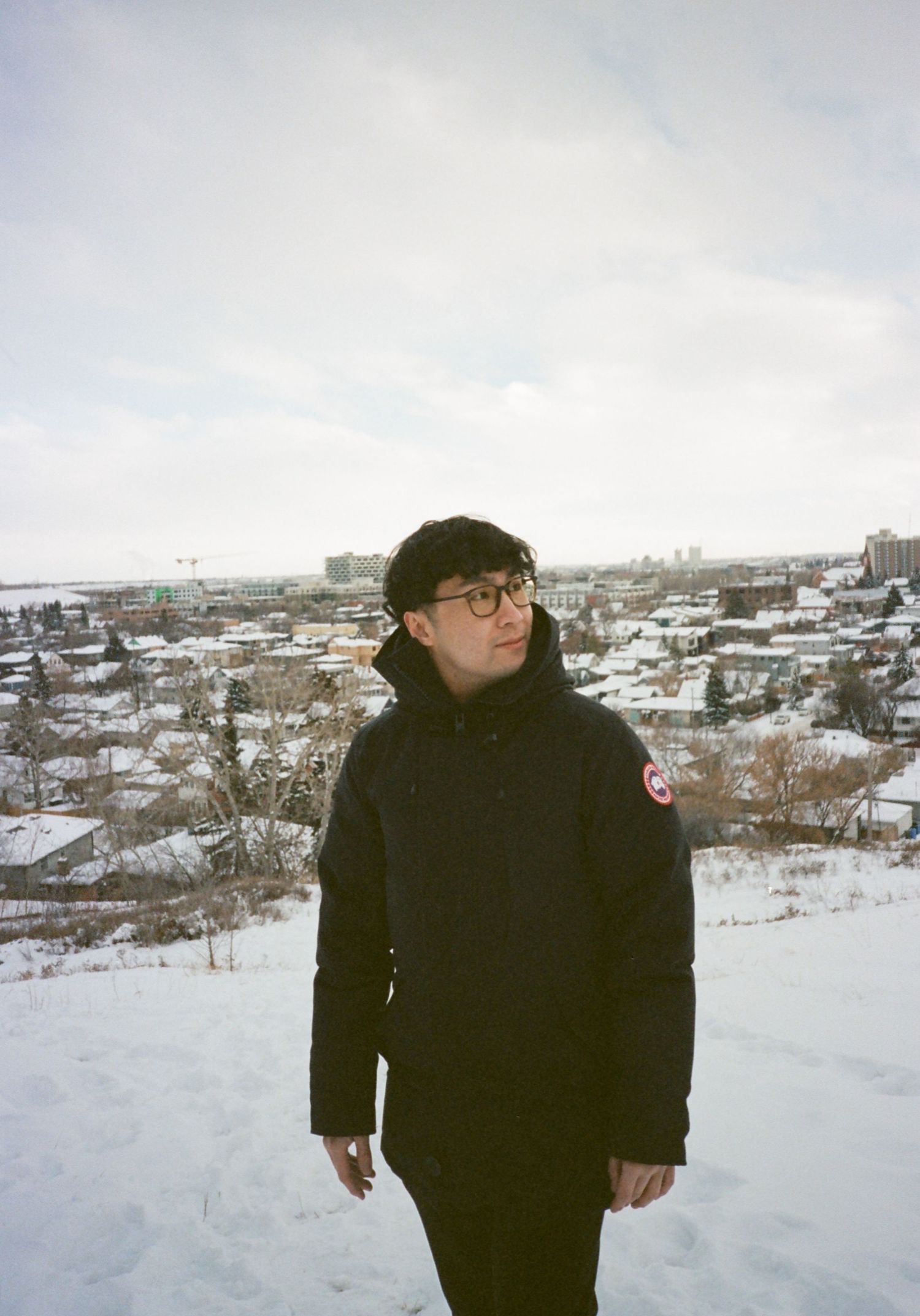 Winter landscape with snow-covered terrain and city buildings visible in the distance.