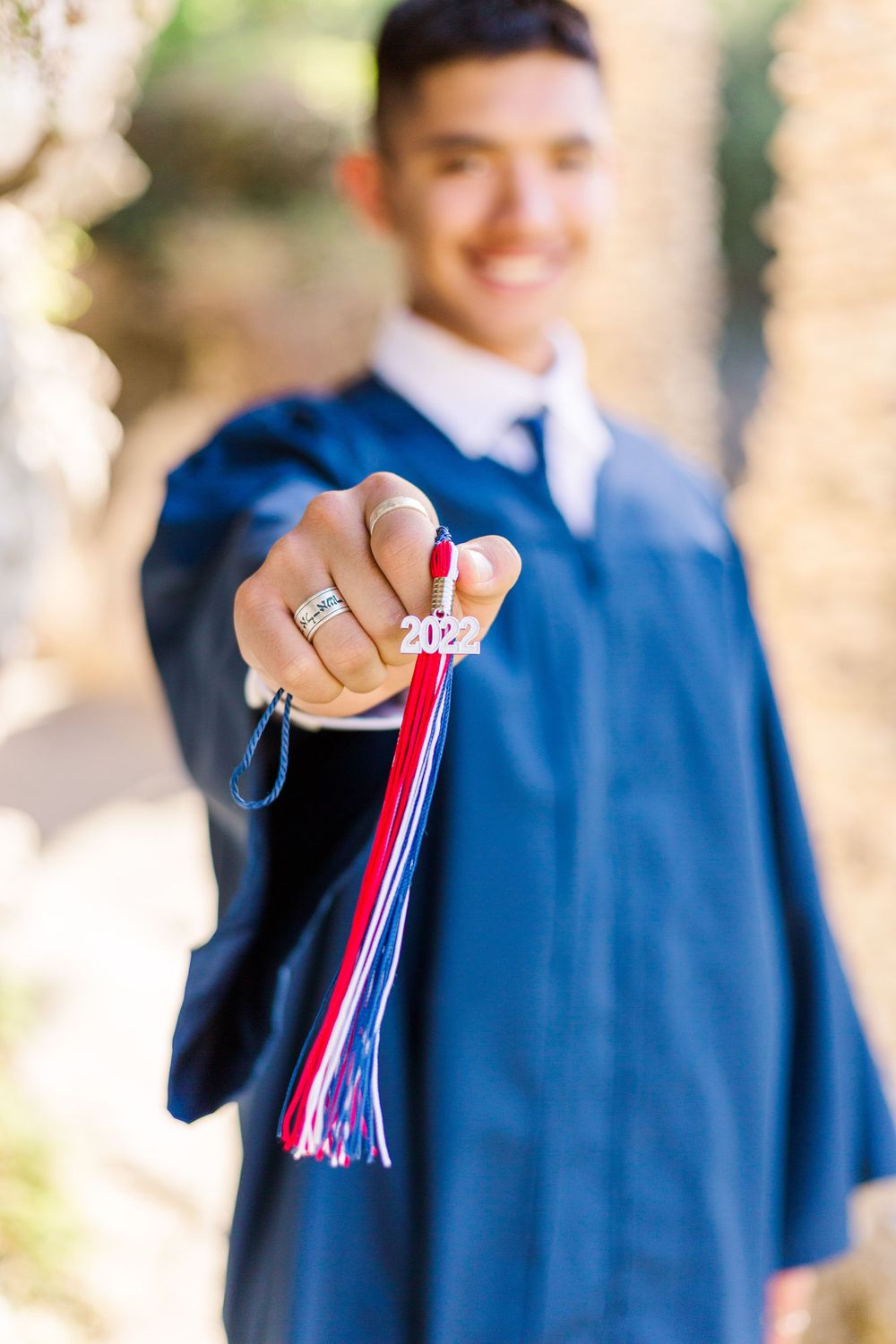 Graduate in blue cap and gown displaying ceremonial graduation tassel.