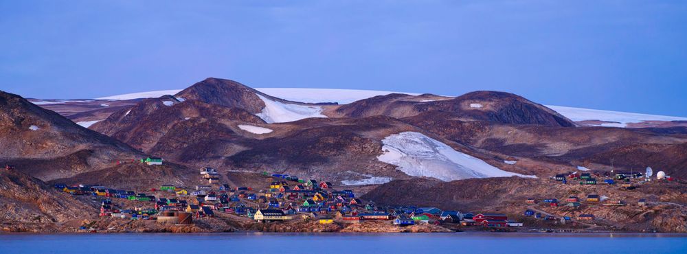Arctic landscape panorama showing mountains and coastal settlement in Greenland.
