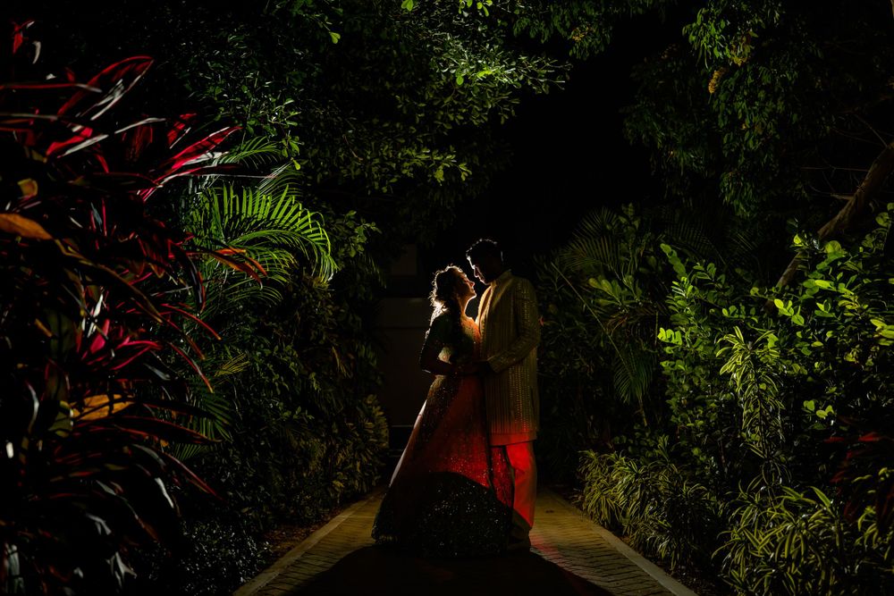 Artistic silhouette portrait in a lush garden setting with dramatic lighting and red tones.