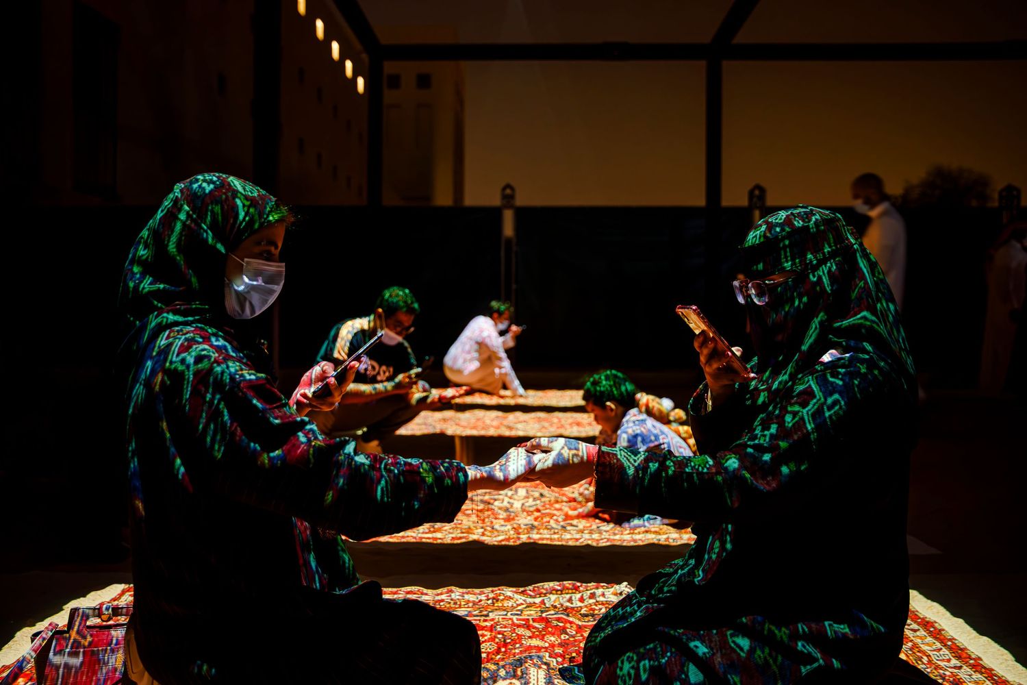 Performers in costume gather around a theatrical set piece in dramatic lighting.