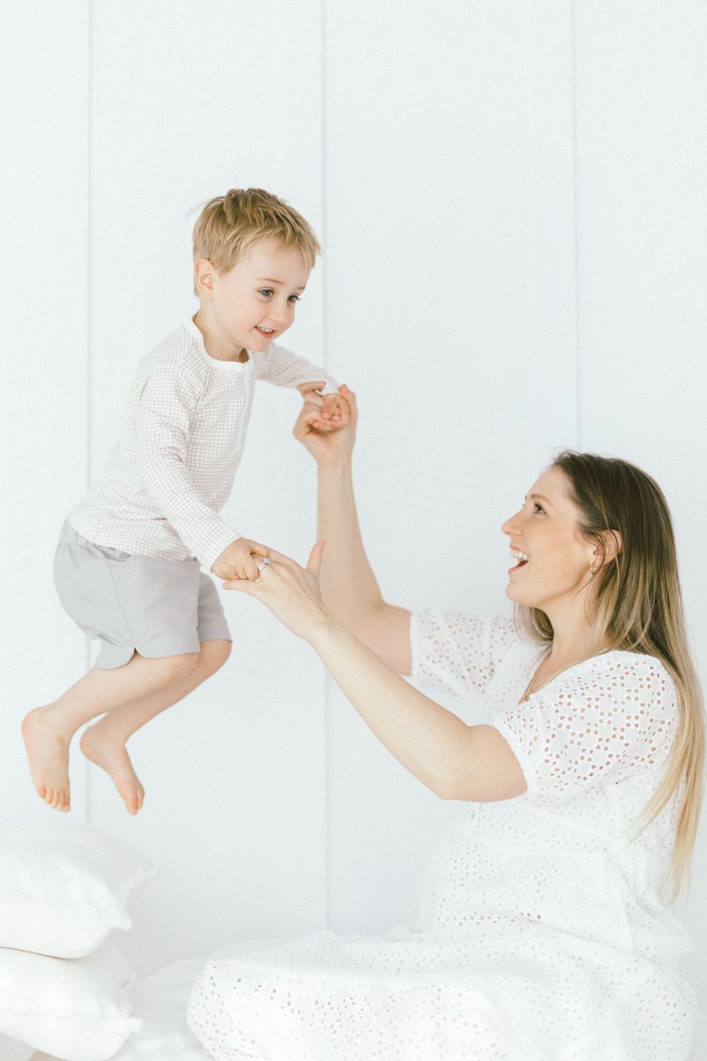 Joyful moment captured as parent lifts child high in white studio setting.