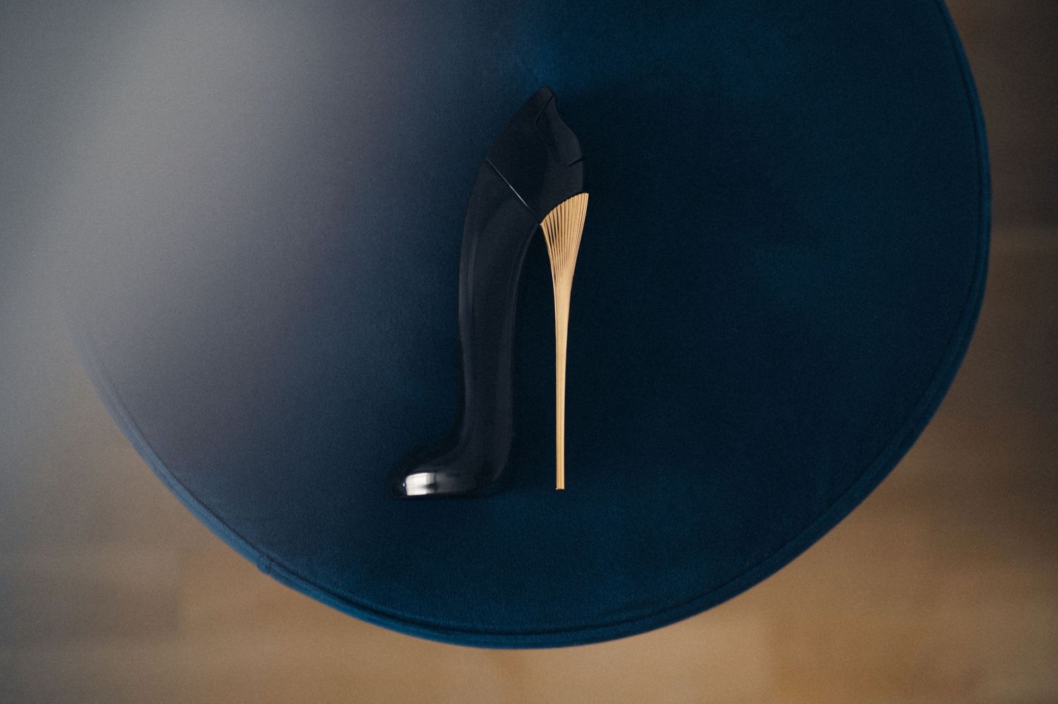 Elegant black stiletto heel silhouetted against dark circular background.