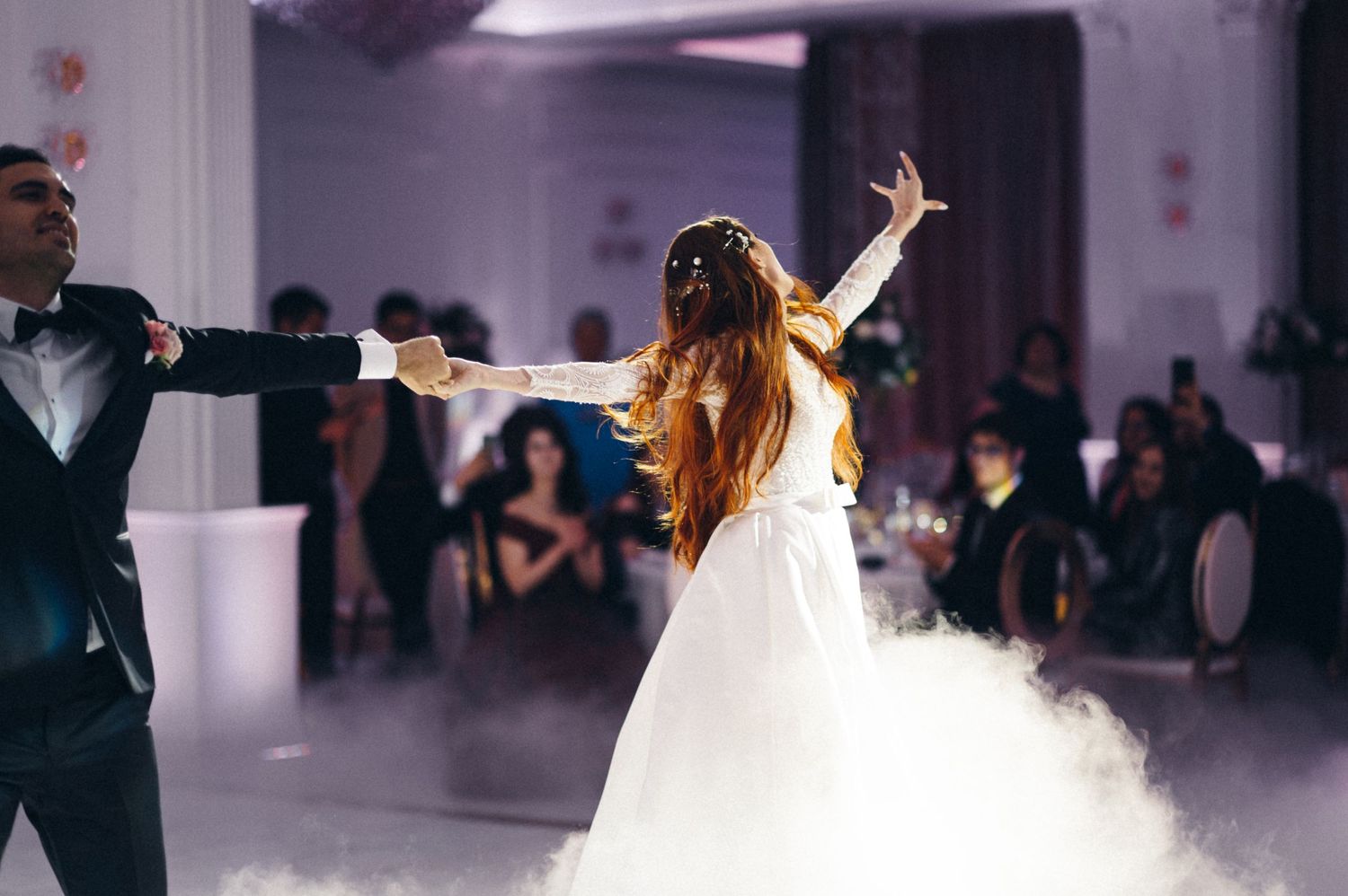 Couple performs their first dance at wedding reception with atmospheric fog on dance floor.