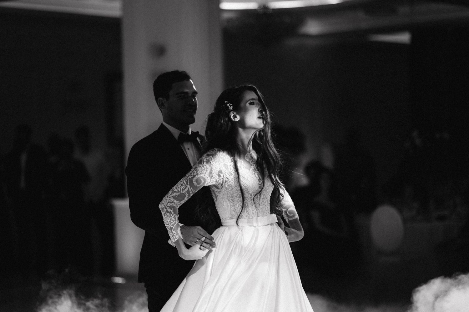 Romantic black and white shot of newlyweds dancing closely at their reception.
