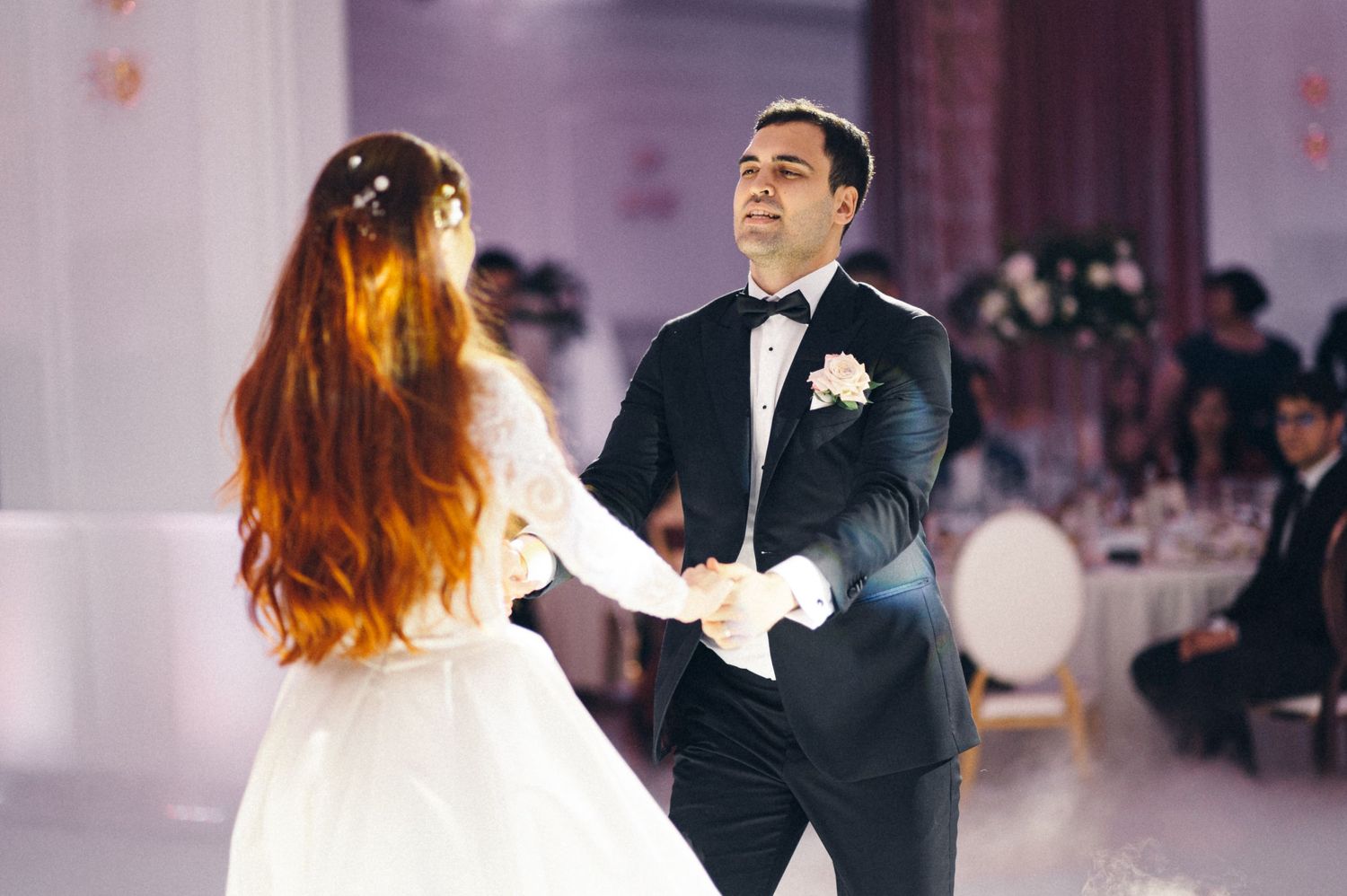 Couple dances together at elegant wedding reception with soft lighting.