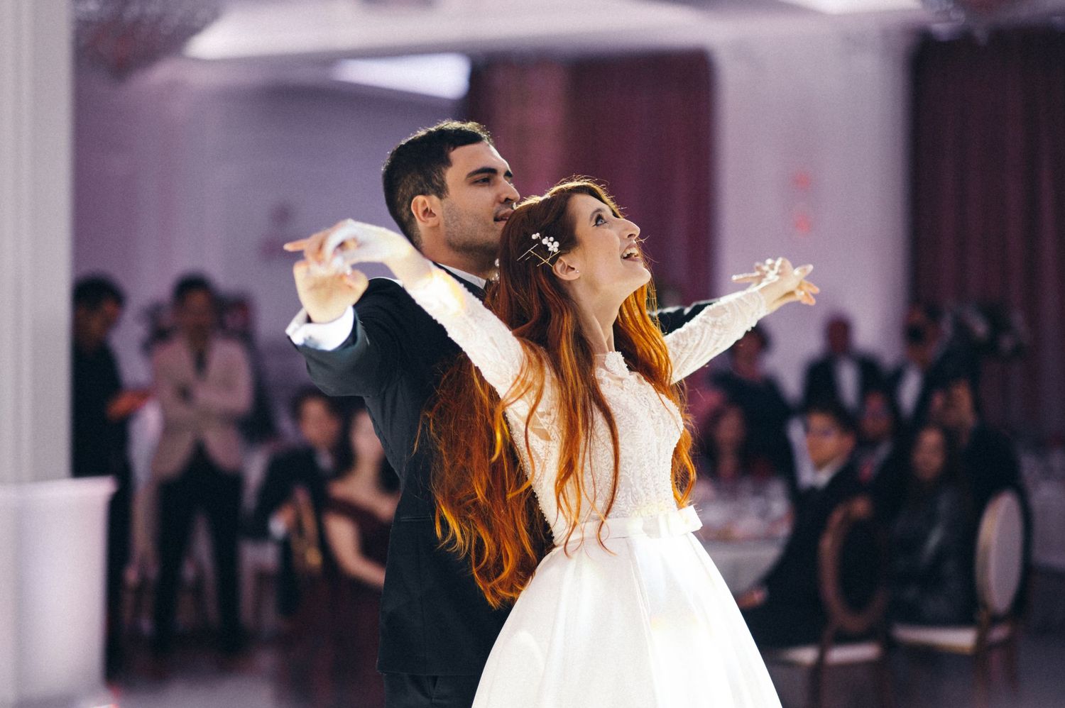 Joyful dancing couple spreads arms wide during wedding celebration dance.