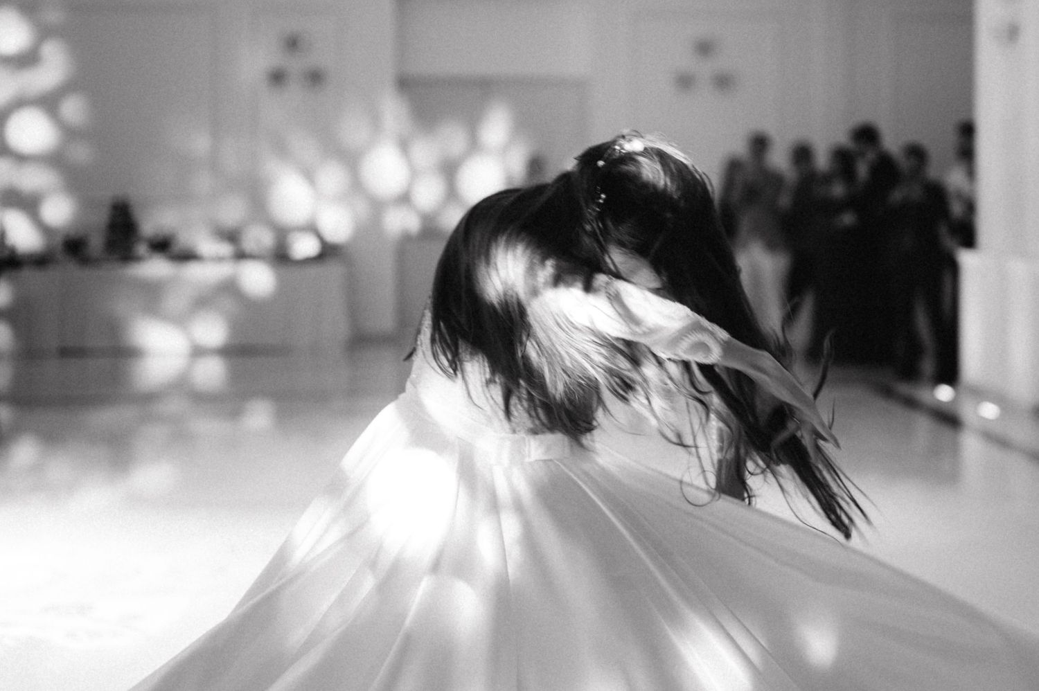 Black and white image of spinning bride with flowing dress and hair in motion.