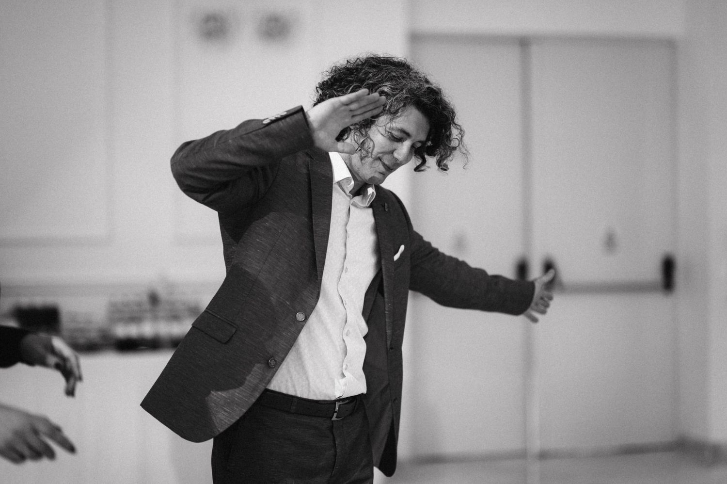 A person in formal attire dances energetically at an indoor event.