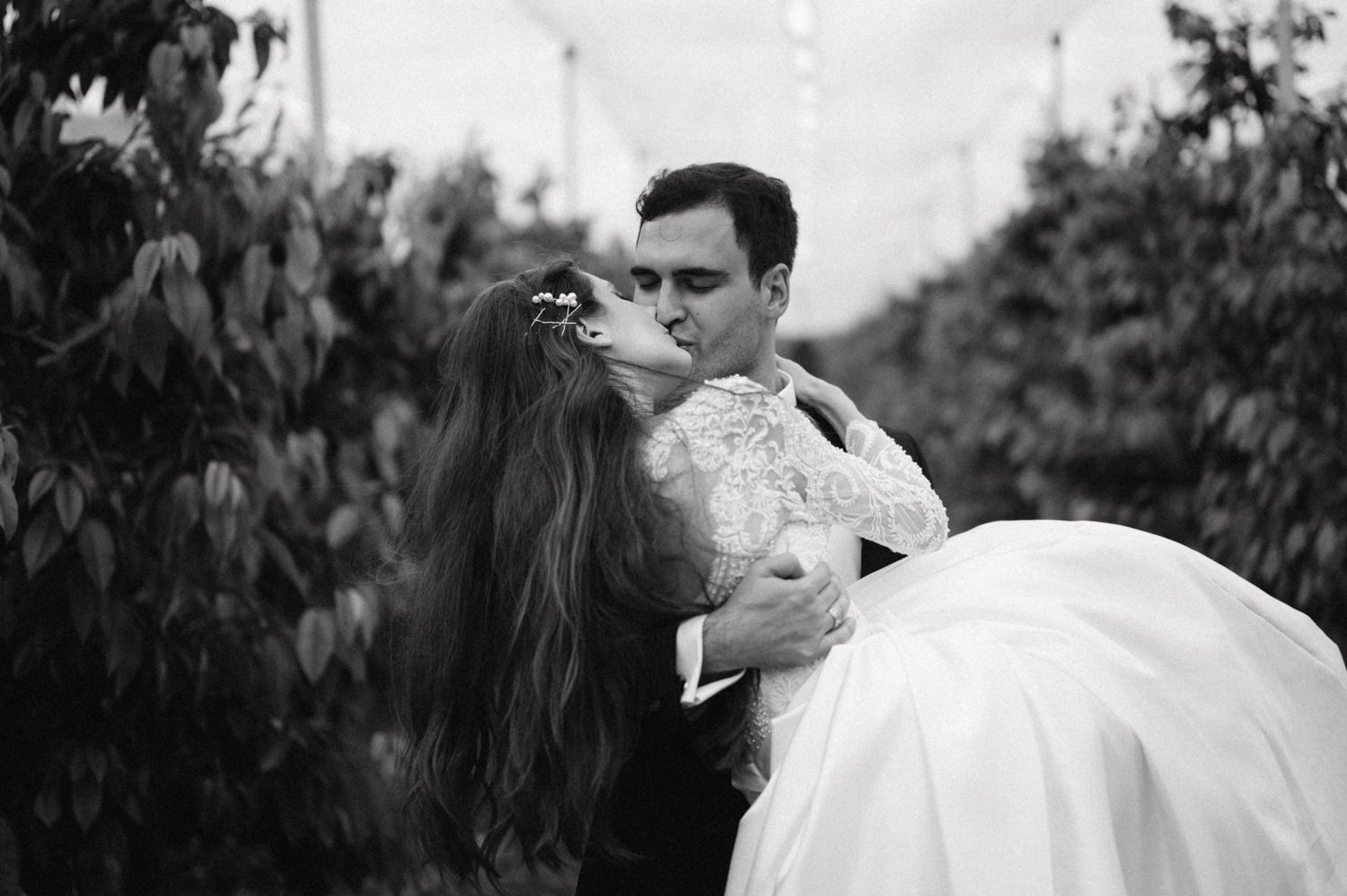 A black and white romantic wedding portrait captured in a garden setting.
