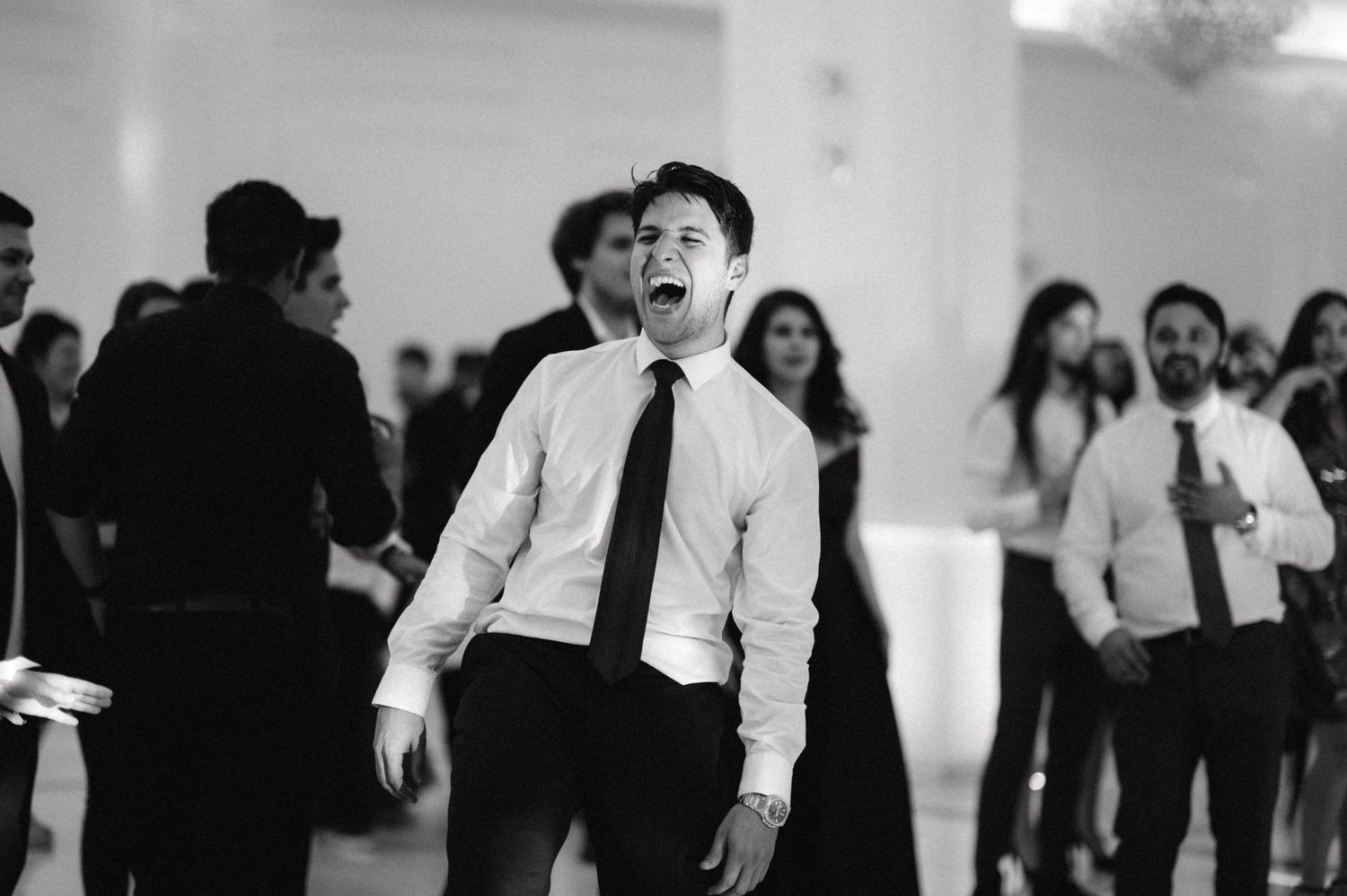 Black and white photo of energetic dancing during indoor celebration.