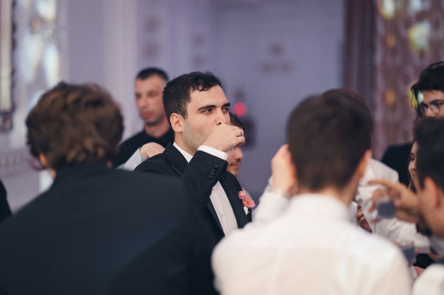 Wedding guests in formal attire enjoying drinks and conversation at a reception.