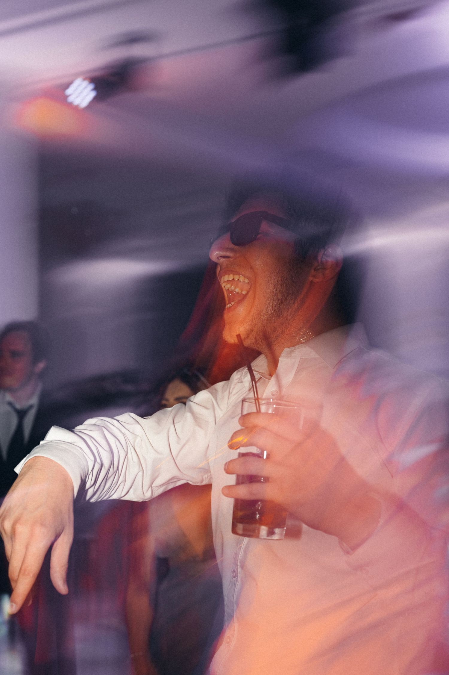 Guest enjoying the party with a drink in hand captured in motion blur with purple lighting.