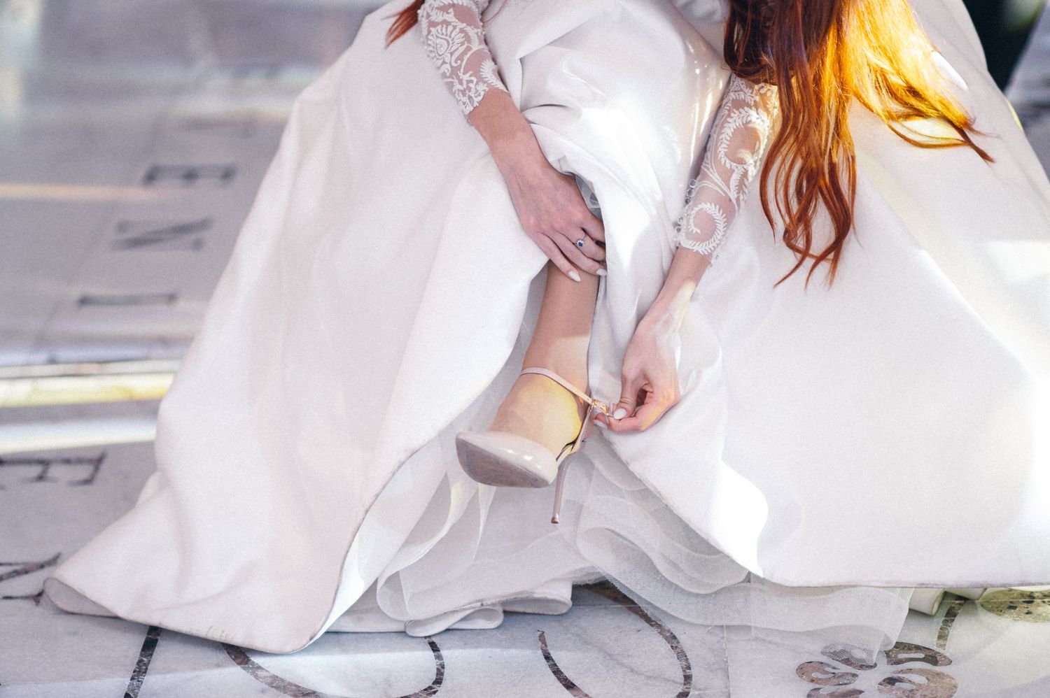 Close-up of bride adjusting her white lace wedding dress.