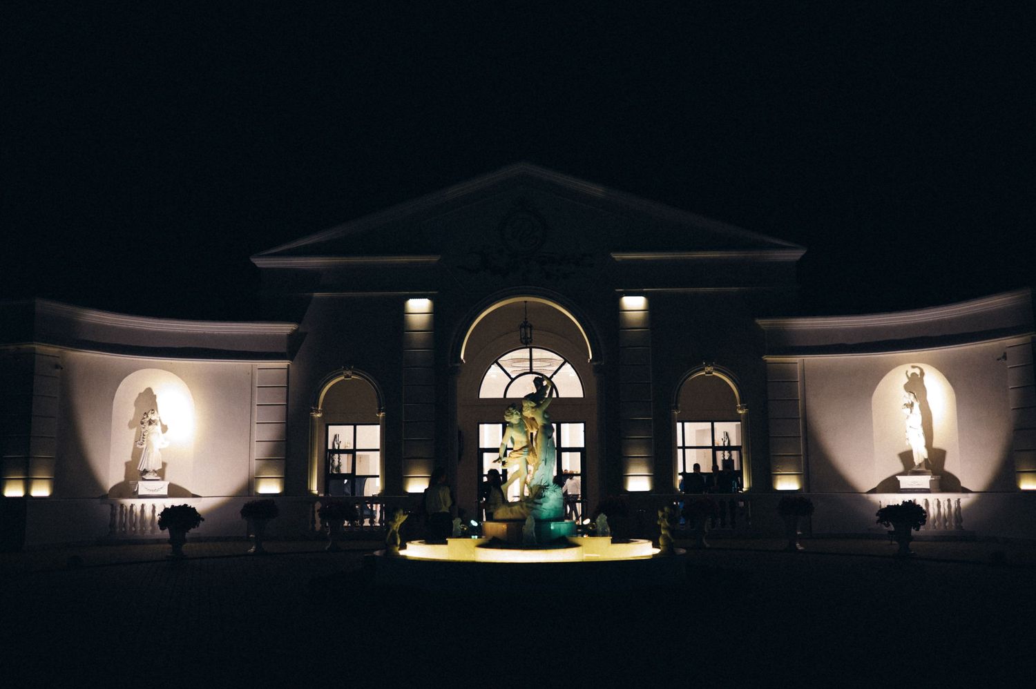 Elegant venue exterior lit up at night with illuminated columns and arched windows.