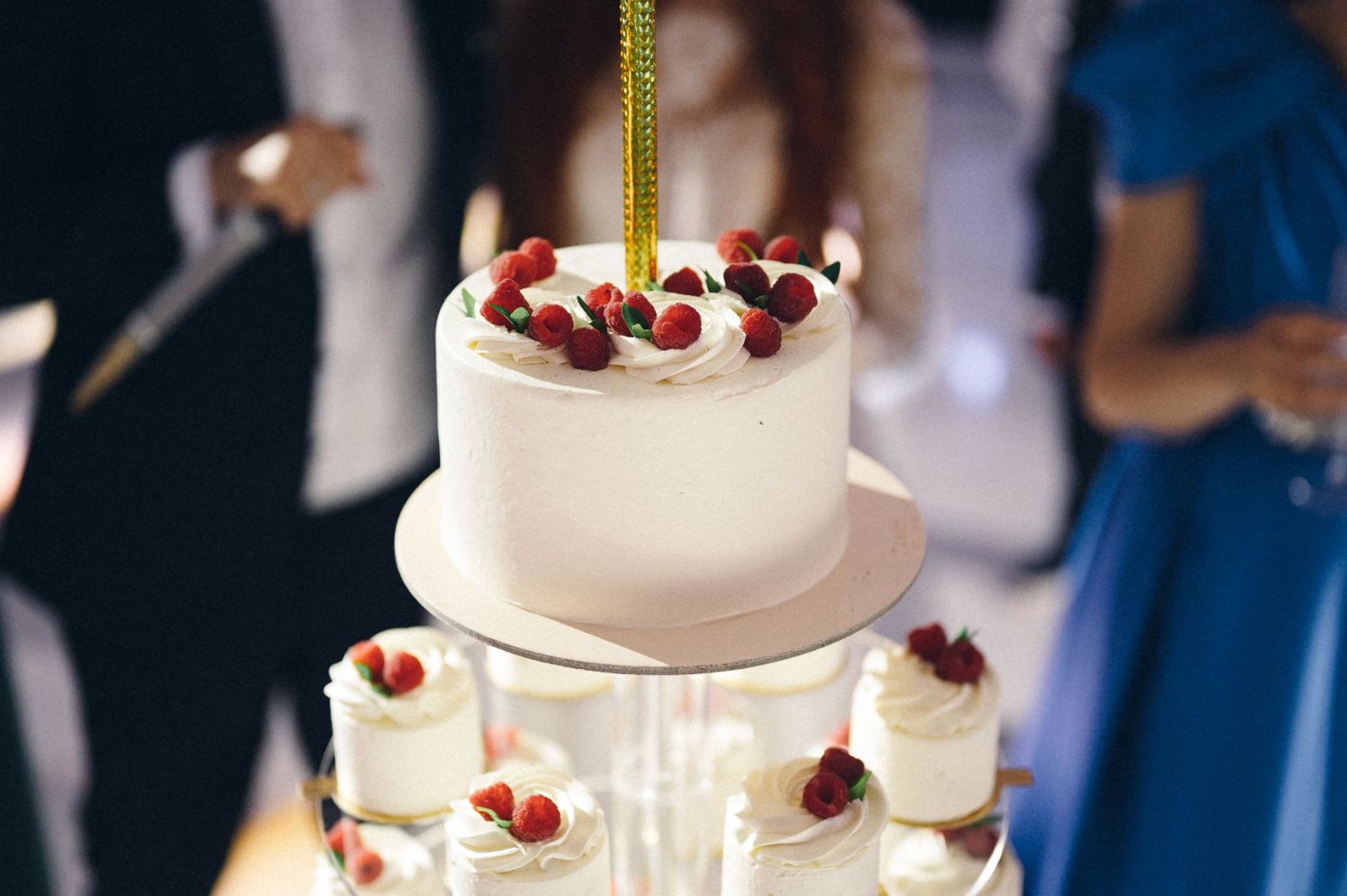 White wedding cake decorated with fresh berries and cranberries on a tiered display stand.