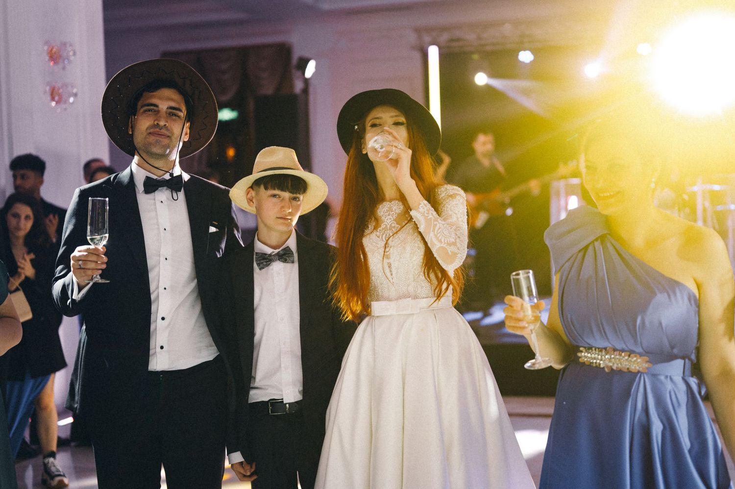 A candid wedding reception moment showing guests in formal attire with atmospheric lighting.