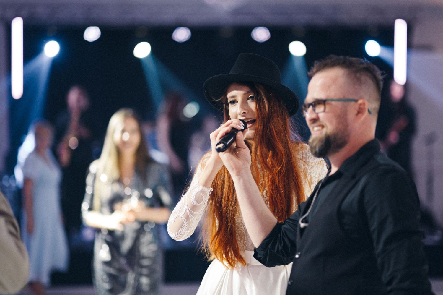 Singer performing at an elegant event with stage lighting in background.