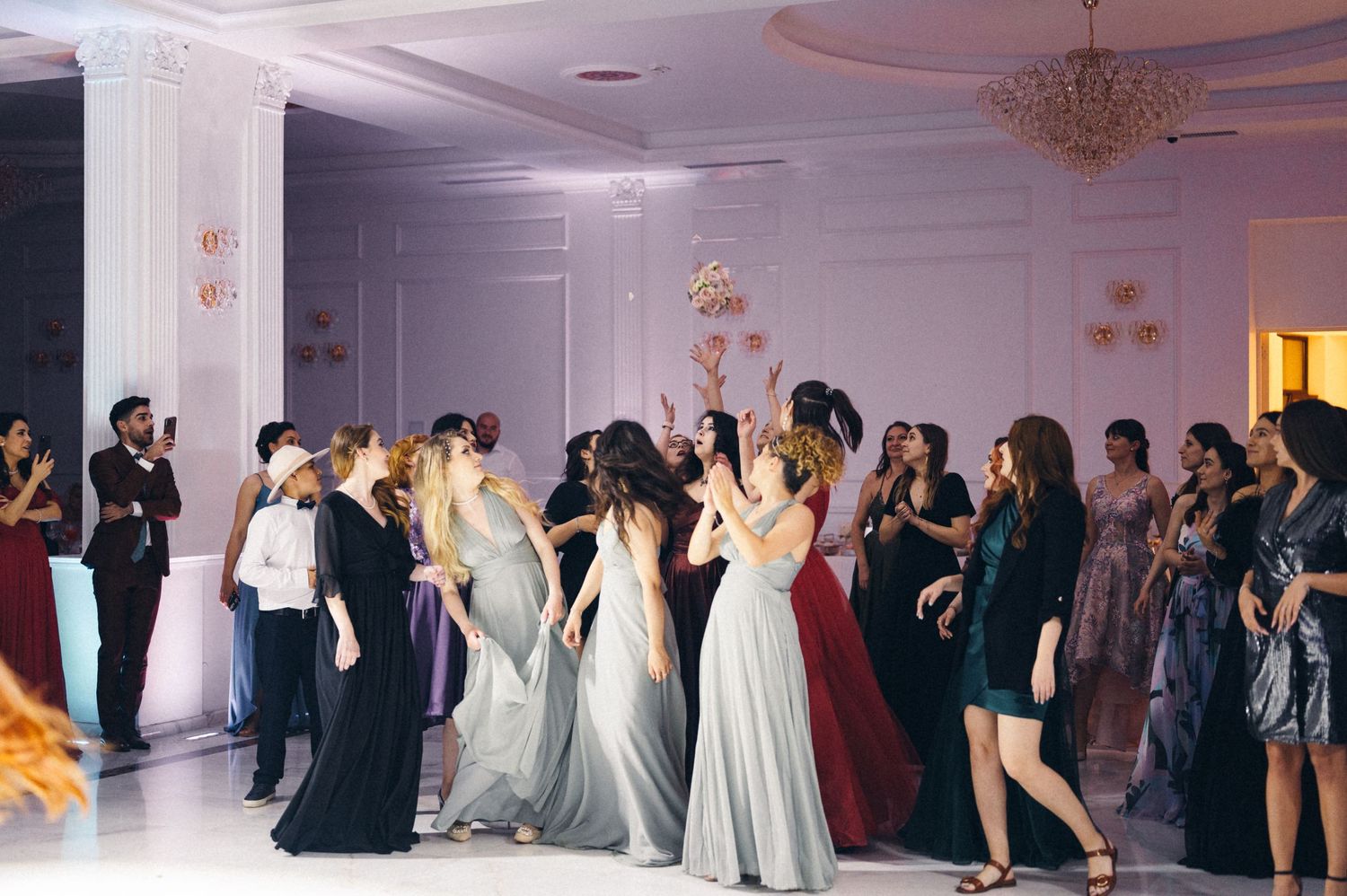 Wedding guests dancing in formal attire at an elegant ballroom reception.