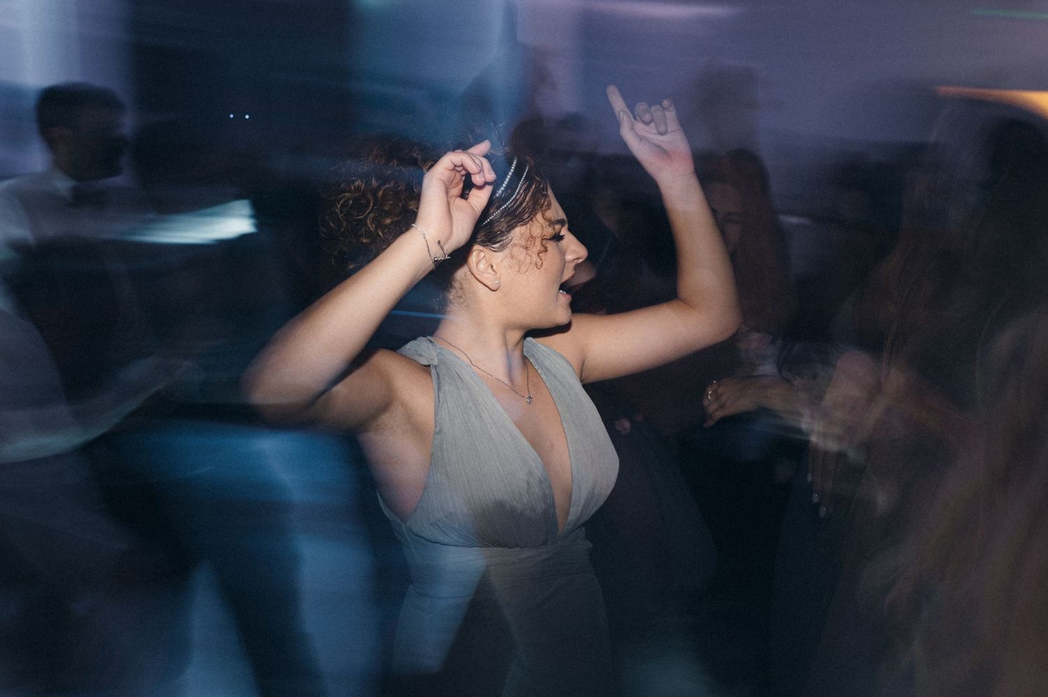 Partygoer dancing energetically in a dimly lit reception venue.