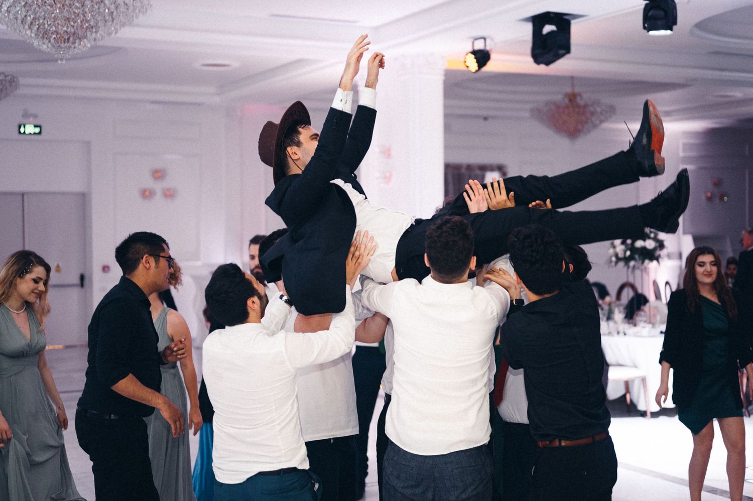 People celebrating at a party with some guests being lifted and tossed in the air during an energetic celebration.