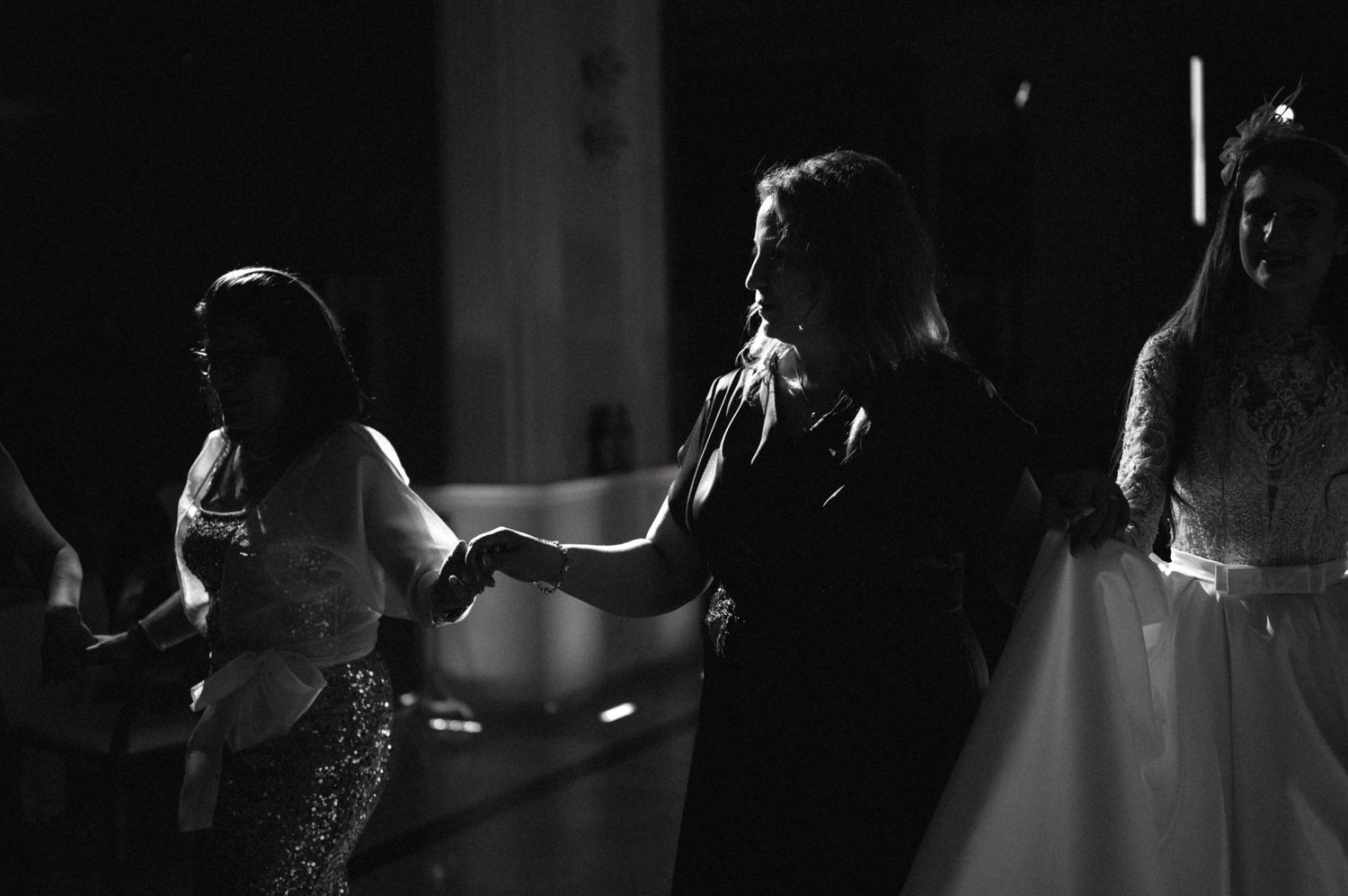 Black and white photo of people dancing and celebrating at a wedding reception.