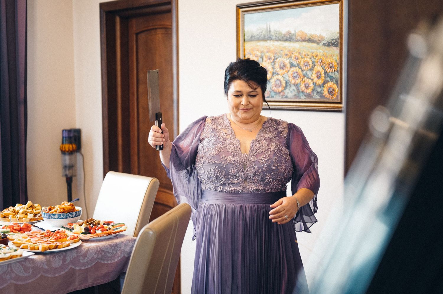 Person in a purple dress standing by an elegant dining table setup.