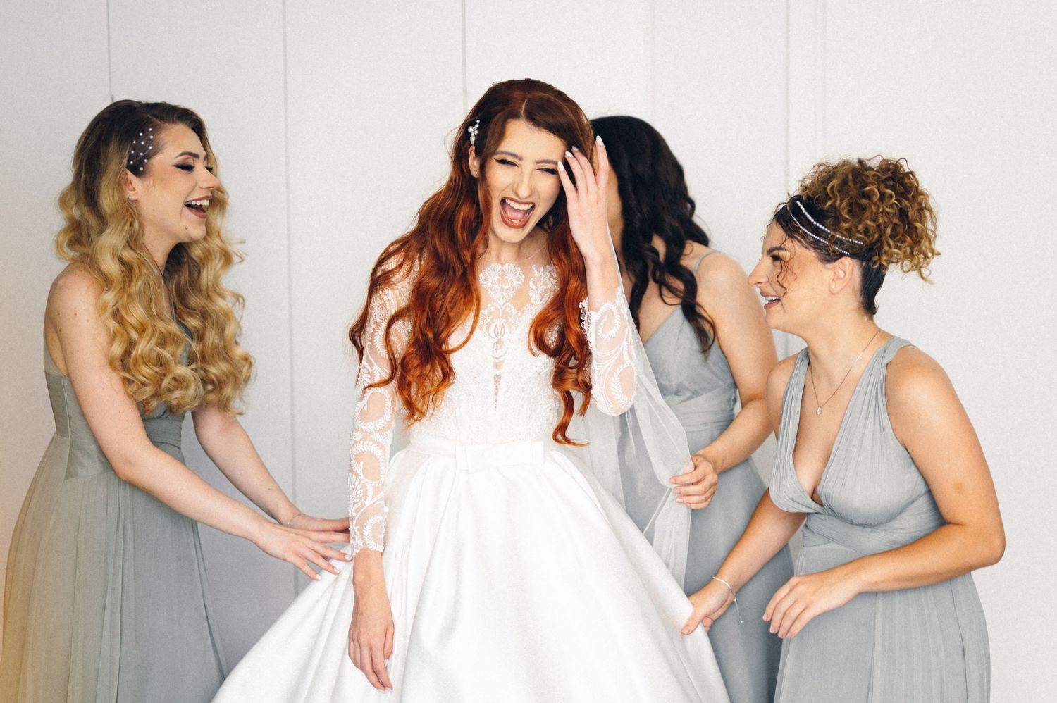 Candid moment of laughter between a bride and her bridesmaids during wedding preparations.