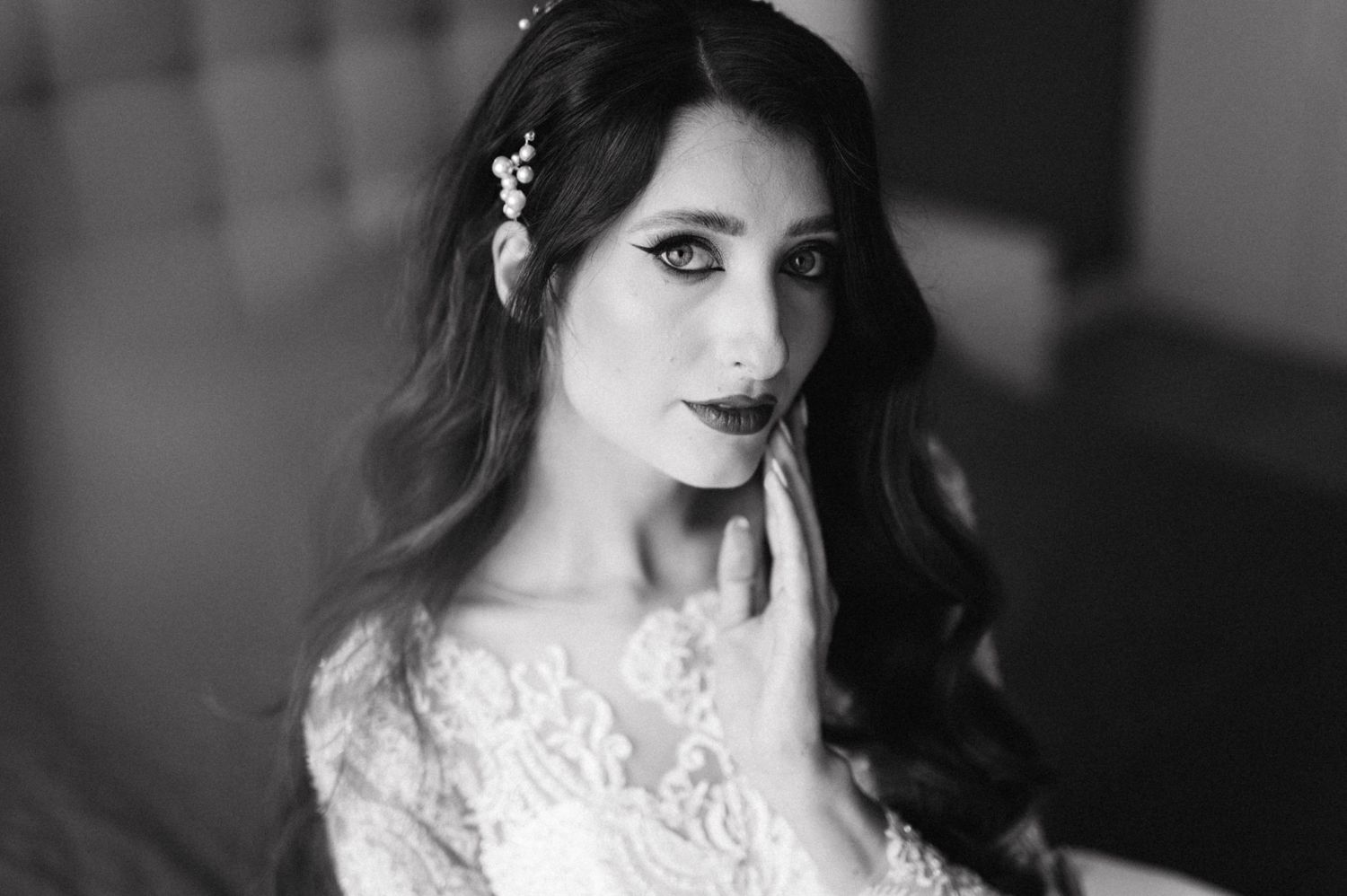Black and white portrait of a bride wearing a lace dress with long dark hair and dramatic makeup.