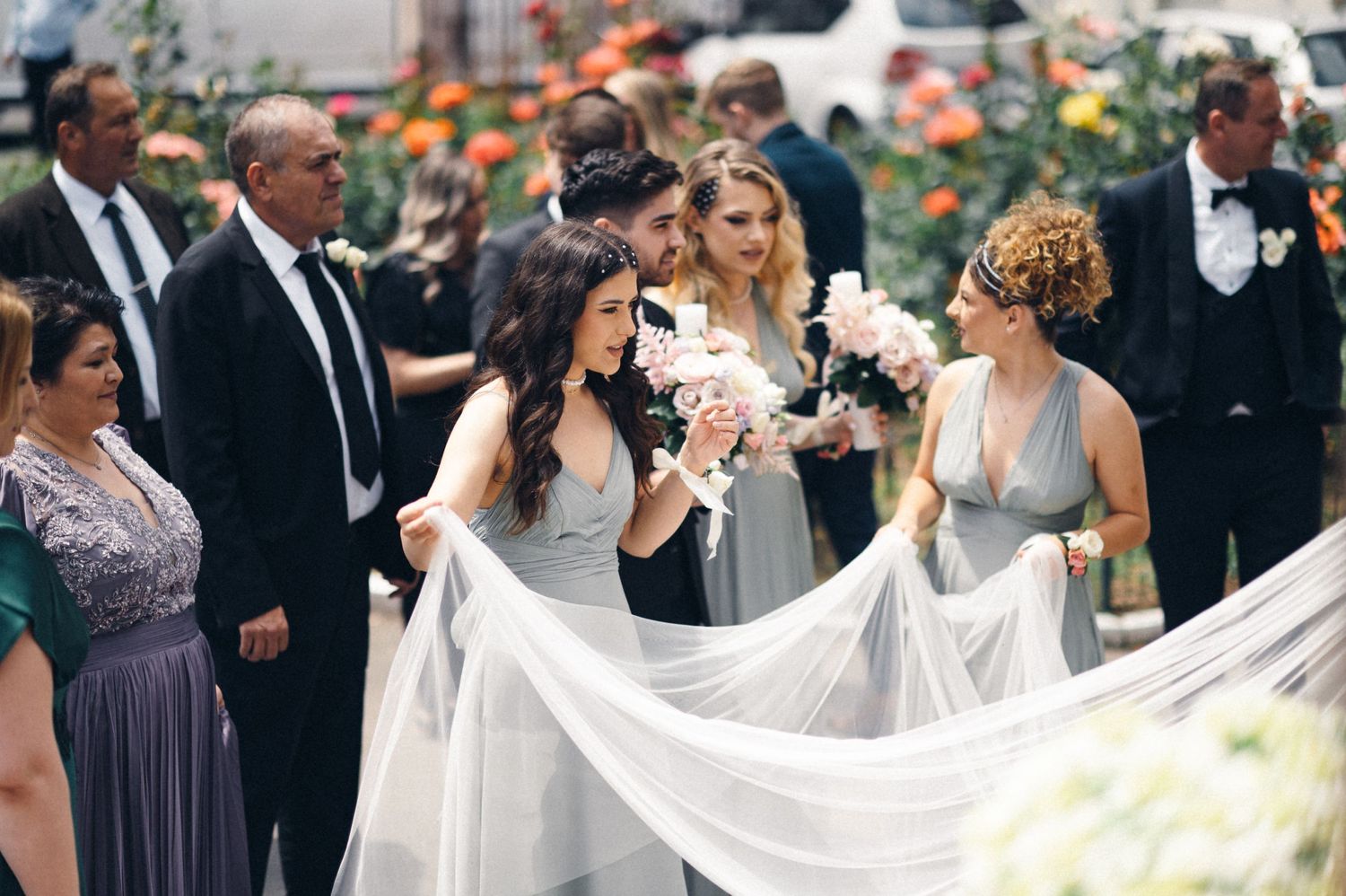 Outdoor wedding celebration with bridal party and flowing white dress details.