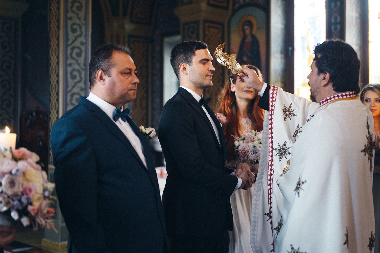 Orthodox wedding ceremony in progress with priest in white robes conducting traditional service.