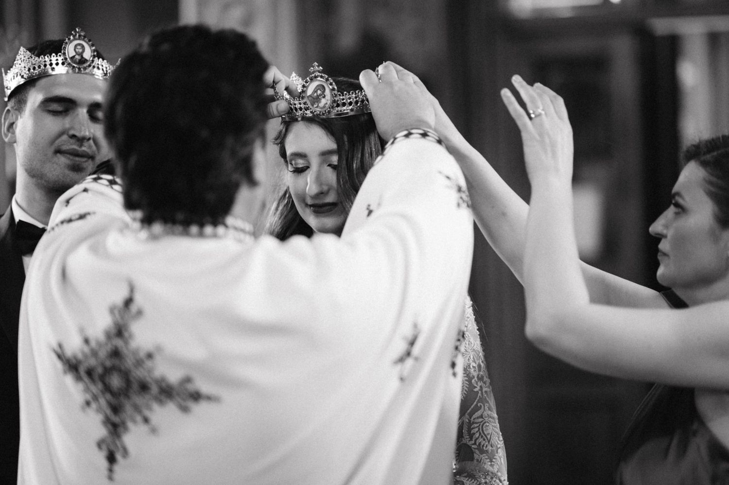 Black and white photo of wedding crowning ritual with ornate crowns being placed.