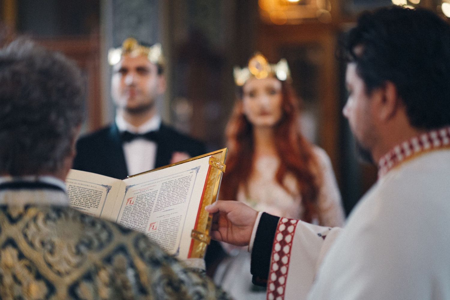 Orthodox priest reading from religious text during traditional wedding ceremony in ornate church.