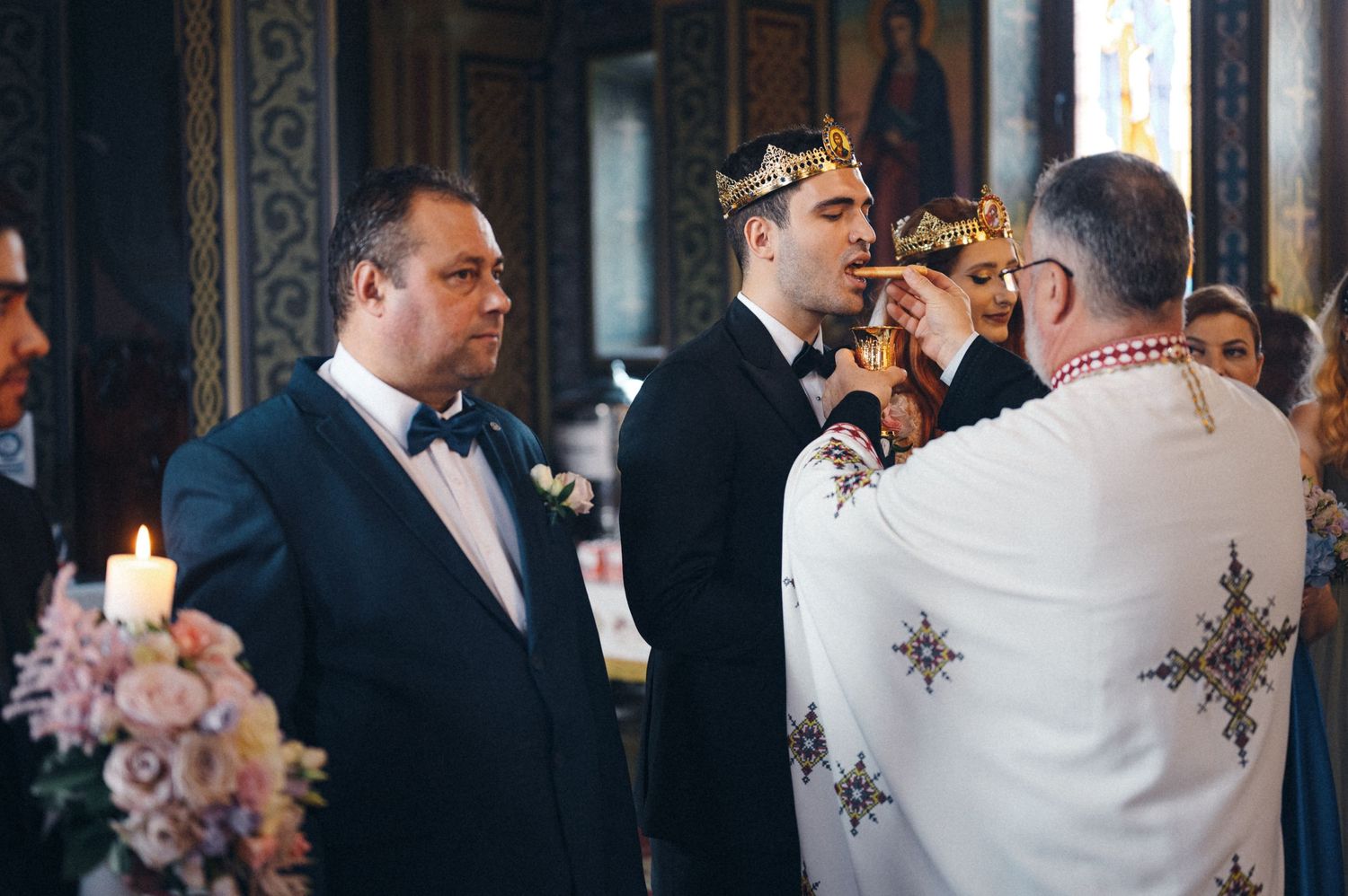 Traditional Orthodox wedding ceremony with priest in embroidered robes performing sacred rituals at the altar.