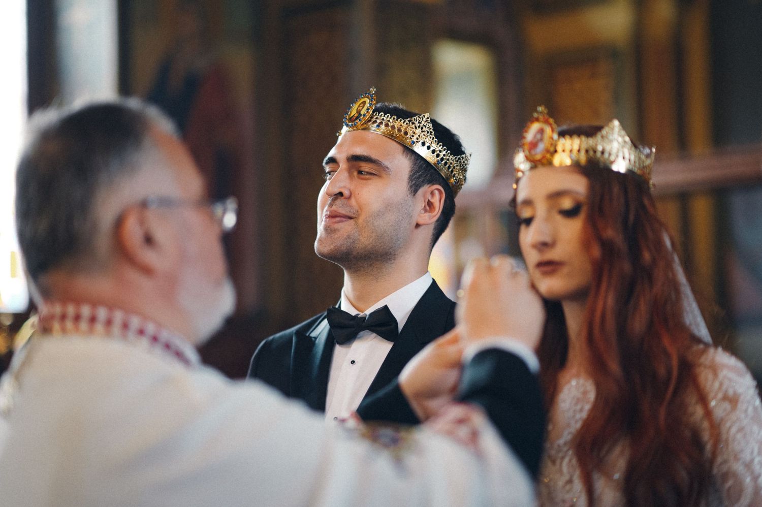 Traditional Orthodox wedding ceremony with crowning ritual in decorated church interior.