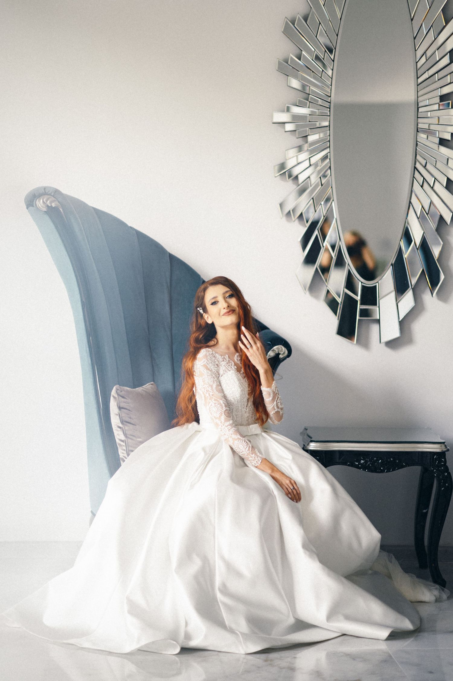 White wedding gown with lace details photographed against modern mirror wall decor.