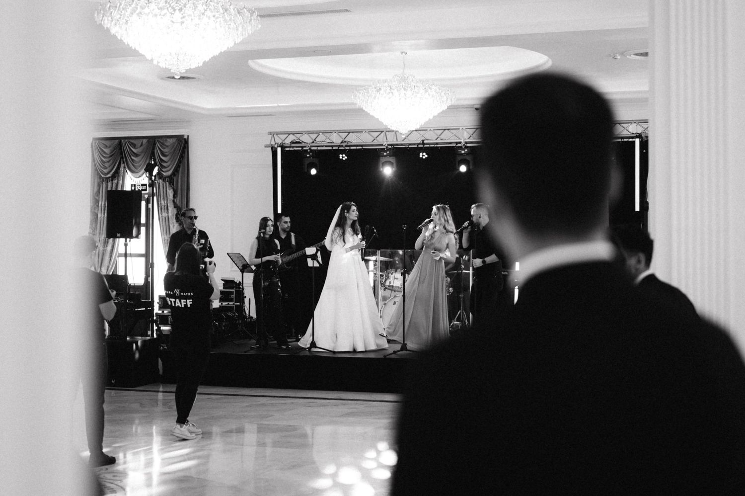 Black and white reception scene with elegant chandeliers and formal dance floor.