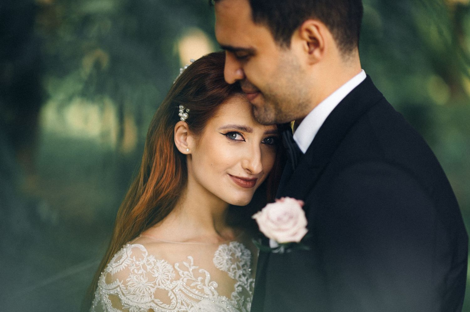 An intimate wedding portrait featuring a delicate lace wedding dress and pink rose boutonniere.
