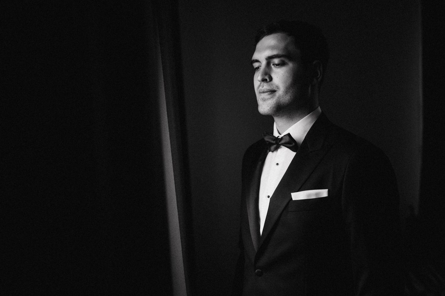 Dramatic black and white portrait of someone in a tuxedo and bow tie.