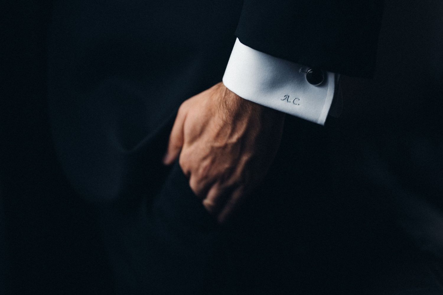 Close-up of a formal suit sleeve with white cuff showing against dark background.