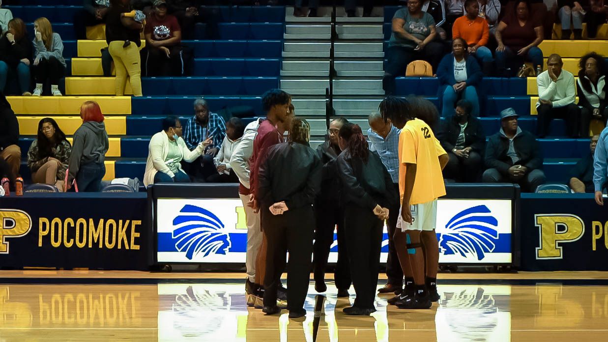 Basketball referees gather on court during a game at Pocomoke gymnasium.