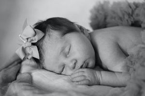 Peaceful newborn sleeping with bow accessory in black and white portrait.